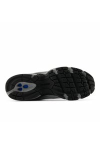 Suola di scarpa sportiva nera con grip in gomma strutturata, con suola esterna grigia e accento blu vicino al tallone per l'ammortizzazione.