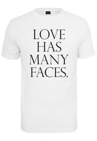 Balta trumpa rankovė t-shirt su ry�škiu juodu tekstu, kuris skaito "MEILĖ TURI DUGA VEIDŲ." Lygus audinys, apvalus kaklo iškirpimas, paprastas stilius.