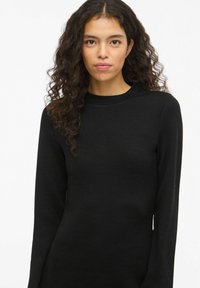 Czarny prążkowany top z długim rękawem, okrągłym dekoltem i dopasowanym fasonem, wykonany z teksturowanej tkaniny o minimalistycznym stylu.