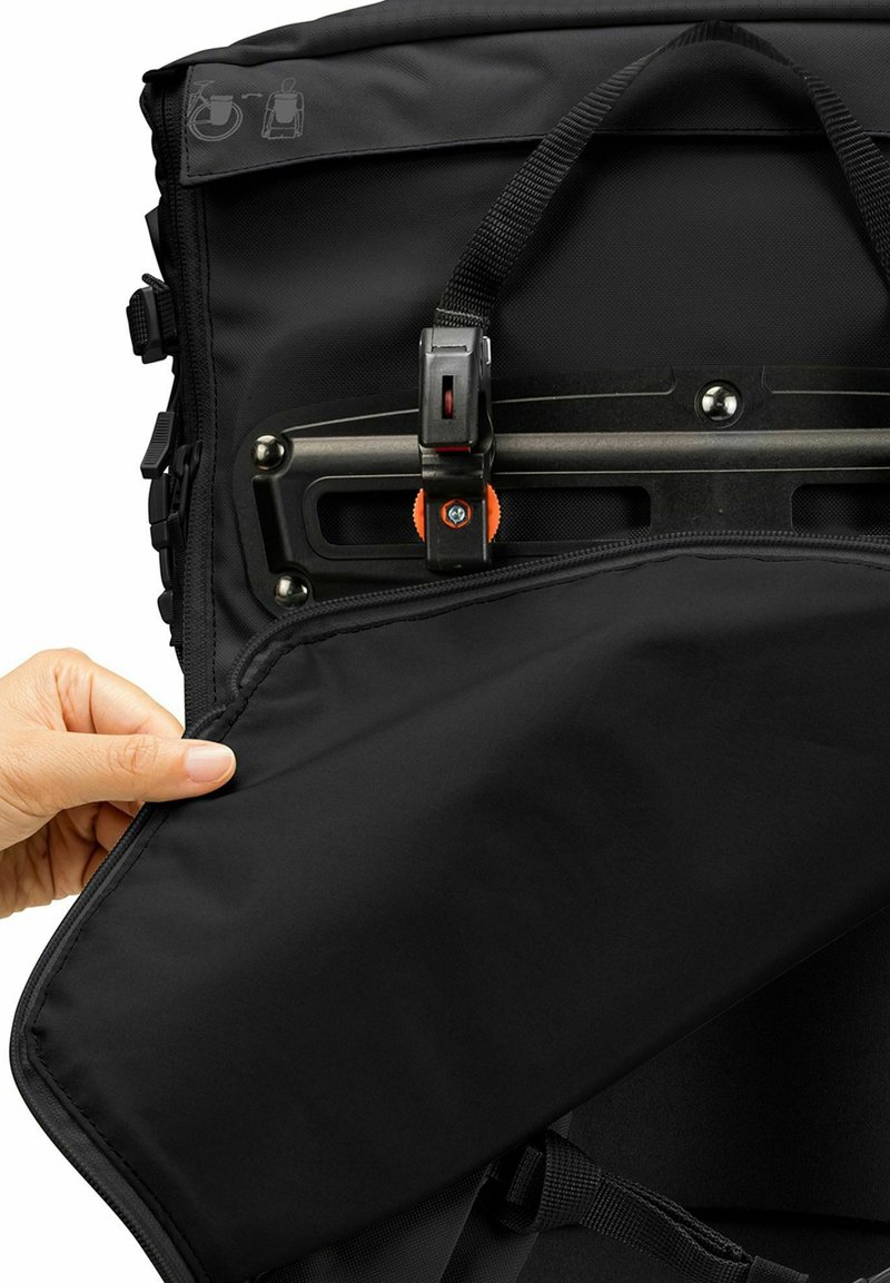 Interior de mochila negra con textura suave, cierre de cremallera y correa ajustable; presenta un acento naranja y herrajes metálicos.