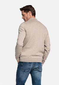 Lichtgrijs sweatshirt met een ronde halslijn, geribbelde manchetten en tailleband. Gepaard met blauwe jeans, wat een casual uitstraling geeft.