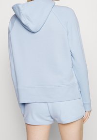 Jasnoniebieska bluza z kapturem o luźnym kroju, z prążkowanymi mankietami i dołem. Miękki materiał, z kieszenią typu kangur na przodzie. W zestawie z dopasowanymi szortami.