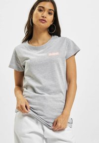 Tricou gri din bumbac, cu decolteu rotund și mâneci scurte. Are un mic logo roz pe piept și o textură netedă.