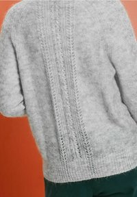 Lichtgrijze gebreide trui met een getextureerd verticale kabelpatroon en open steken langs de achterkant. Zacht, donzig materiaal.