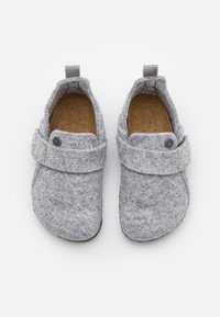 Szare filcowe kapcie z miękką fakturą, szerokim paskiem z detalem w postaci guzika oraz wyściełaną wkładką zapewniającą komfort.