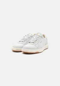 Baskets blanches en cuir avec une texture lisse, accents gris clair, design bas, bout rond et semelle en caoutchouc contrastante.