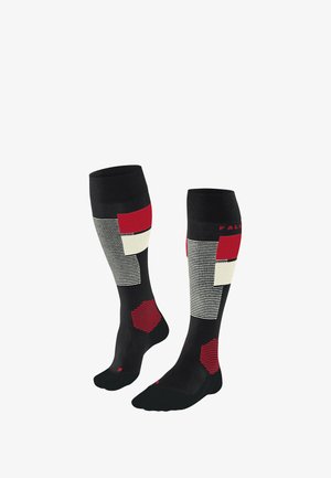 Schwarze kniehohe Socken mit geometrischen Mustern, die rote und weiße Blöcke zeigen. Weiches Material mit geripptem Muster und verstärkter Ferse.