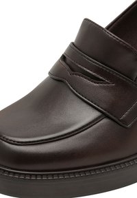 Κοντινή λήψη ενός σκούρου καφέ δερμάτινου loafer με διακοσμητική λουρίδα και ραμμένα σχέδια στο άνω μέρος και τη σόλα.