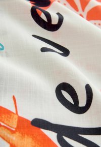 Baumwollstoff mit weißem Grund, der kräftigen schwarzen Text, lebhaften orangen und aquafarbenen Mustern sowie einer glatten, leicht durchscheinenden Textur zeigt.