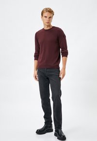 Bordeaux brei trui met lange mouwen, ronde hals; gecombineerd met zwarte jeans en stevige zwarte laarzen; gladde textuur, slim fit ontwerp.