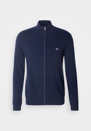 Marine blauwe ritscardigan in een zachte wolmix. Kenmerken zijn een hoge kraag, aansluitende manchetten en een klein geborduurd logo op de borst.