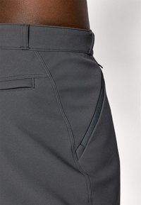 Grijze sportshorts van een gestructureerde stof, met een zijzak en contrasterende ritsdetails, en een gestructureerde tailleband.