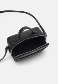 Borsa a tracolla in pelle nera con chiusura zip, dotata di manico superiore, texture liscia e dettagli con logo all'interno.