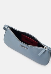 Jasnoniebieska skórzana kopertówka o g�ładkiej fakturze, z srebrnym zapięciem na zamek i czerwonym wnętrzem z przegródką na karty, ozdobioną tłoczonym logo.