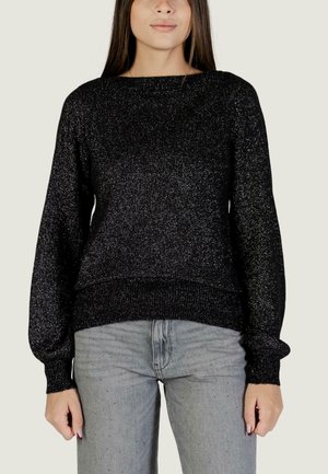 Maglione nero in maglia con una texture scintillante, scollatura a barca e polsini e orlo a costine. Abbinato a jeans dritti grigio chiaro.