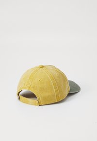 Yellow and green cap with a soft, textured fabric; features six panels, a curved brim, and an adjustable strap at the back.