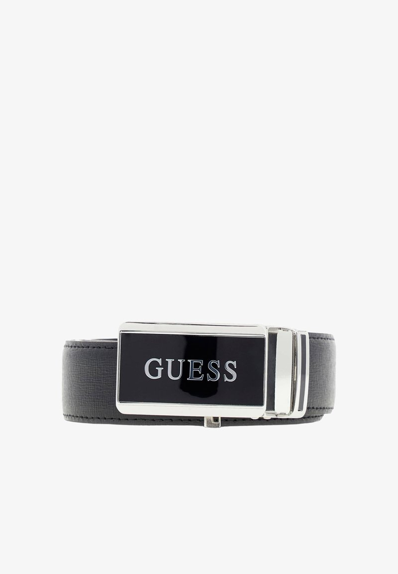 Ceinture en cuir noir avec une boucle rectangulaire argentée brillante portant le mot « GUESS » en majuscules sur fond noir.