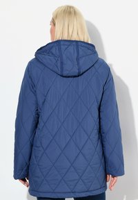 Chaqueta acolchada de puffer en color navy con capucha, que presenta un patrón de diamantes, mangas largas y un diseño de longitud media. Textura lisa y material ligero.