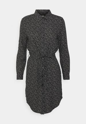 Vestido camisetado negro de manga larga con un patrón de puntos irregulares blancos, botones en la parte delantera, cuello y cinturilla ajustable.