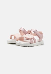Rosa sandaler med metalliske stropper, hvite gummisåler, justerbare borrelåslukkinger og subtil merking på siden.