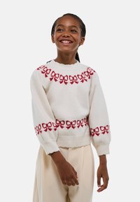 Pull en tricot crème avec des motifs de n œuds rouges au niveau du col et des manches, présentant un ourlet arrondi et des poignets côtelés. Texture douce.