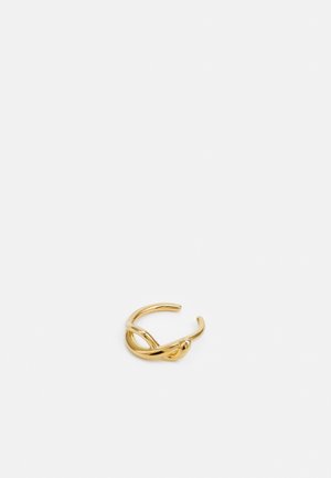 Gold-tone open ring with a twisted knot design on a plain light gray background.
