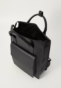 Mochila rectangular de cuero negro con asa en la parte superior, bolsillo frontal, compartimento con cremallera abierta y correas de hombro ajustables sobre un fondo blanco.