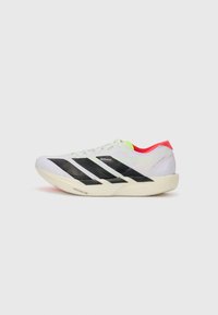 White running shoe with black stripes, neon green accents, and a red heel. Features a lightweight design and textured sole for grip.