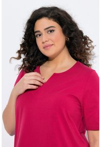 T-shirt magenta con scollo a V, maniche corte e vestibilità rilassata. Tessuto morbido e liscio, con una sottile cucitura dettagliata all'collo.