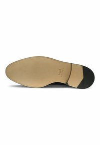 Suola della scarpa in gomma color tan, con superficie liscia e leggere scanalature. Accento nero sul tallone e dettagli del logo inciso vicino al centro.