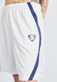 Baltos sportinės šortai su tekstūruotu raštu, tamsiai mėlyna šonine juosta ir trikampiu „Nike“ logotipu ant kairės kojos. Su elastingu juosmeniu.