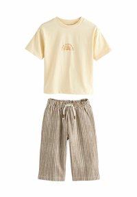Cremefarbenes T-Shirt mit kurzen Ärmeln, bedruckt mit dem Text "Ich bin Sonnenschein" und einer Sonnen-Grafik, kombiniert mit braunen und weißen, vertikal gestreiften Jogginghosen mit Kordelzug.