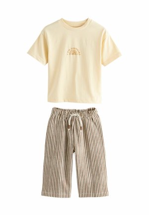 Cremefarbenes T-Shirt mit kurzen Ärmeln, bedruckt mit dem Text "Ich bin Sonnenschein" und einer Sonnen-Grafik, kombiniert mit braunen und weißen, vertikal gestreiften Jogginghosen mit Kordelzug.