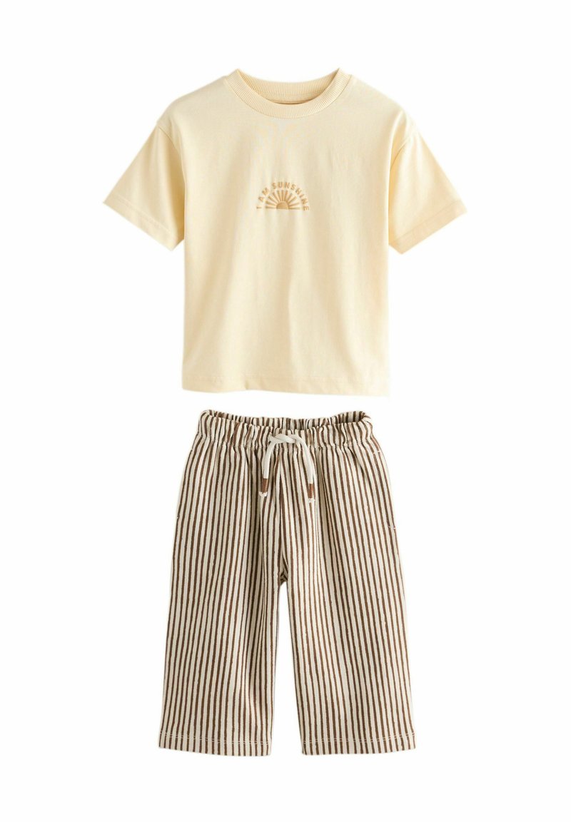 Cremefarbenes T-Shirt mit kurzen Ärmeln, bedruckt mit dem Text "Ich bin Sonnenschein" und einer Sonnen-Grafik, kombiniert mit braunen und weißen, vertikal gestreiften Jogginghosen mit Kordelzug.