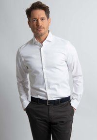 Witte, lange mouw, knoopshirt met een klassieke kraag, een gladde textuur en een subtiele glans, gecombineerd met donkere broek en een zwarte riem.