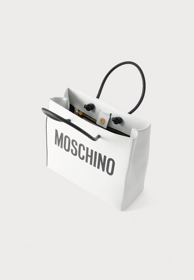 Λευκή ορθογώνια γυναικεία τσάντα με μαύρες λαβές, χρυσό φερμουάρ και το λογότυπο "MOSCHINO" εκτυπωμένο με μεγάλα μαύρα γράμματα στο εμπρός μέρος.