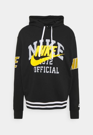 Sudadera negra con cordones blancos, que presenta gráficos de Nike en amarillo y gris, un dobladillo a rayas y acentos de logotipo en las mangas.