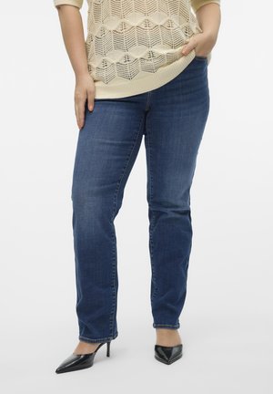 Denim jeans in dark blue with a straight fit, featuring a classic five-pocket design and soft texture. Worn with black pointed heels.