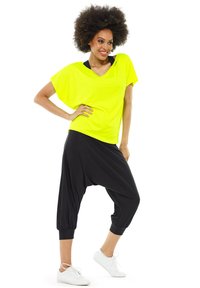 Yellow oversized short-sleeve top paired with loose black harem pants and white sneakers. The fabric appears soft and lightweight.