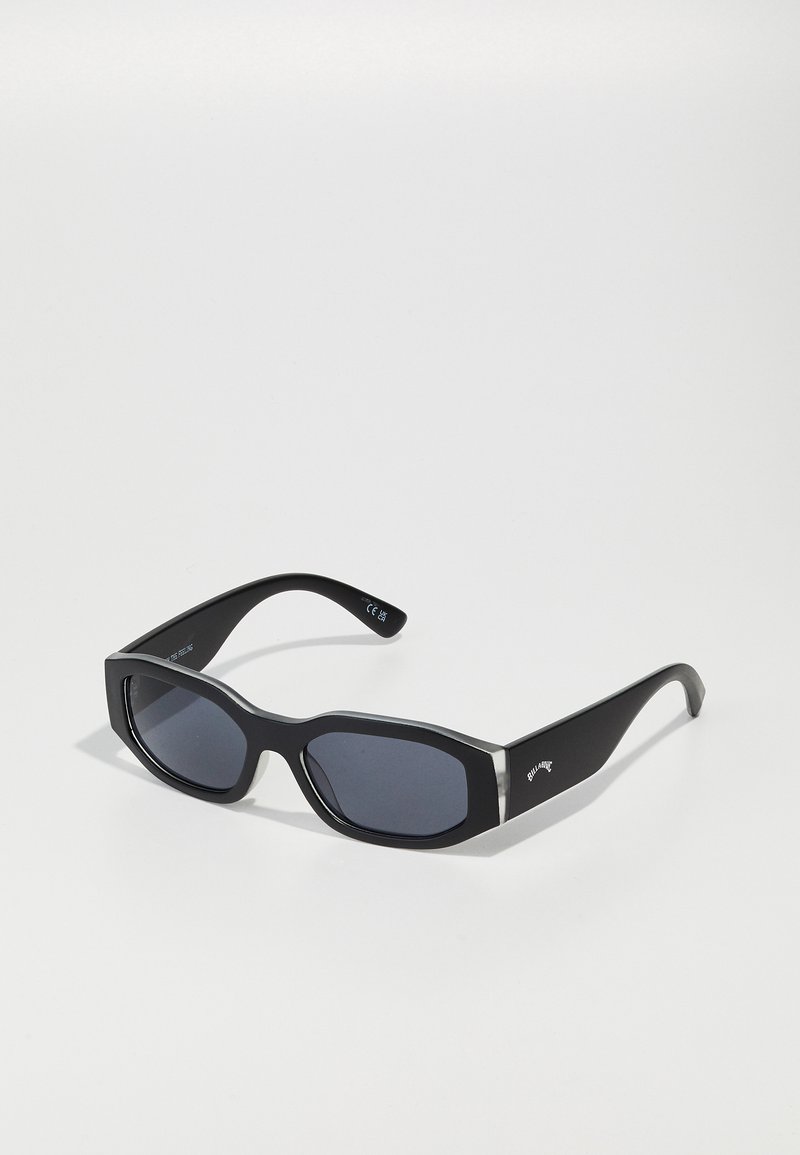 Black sunglasses with a chunky shape, dark lenses, and glossy accents on the frame. Silver-toned hardware detail near the temples.
