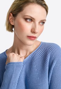 Hellblauer gestrickter Pullover mit V-Ausschnitt. Verfügt über eine strukturierte Rippung und lange Ärmel und zeigt einen weichen, atmungsaktiven Stoff.