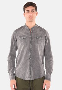 Camicia grigia con bottoni realizzata in tessuto testurizzato. Caratterizzata da un colletto alla mandarino, due tasche sul petto e dettagli di cucitura in vista.