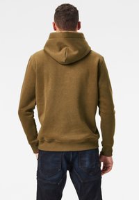 Sudadera verde oliva con una gran capucha ajustable, puños acanalados y dobladillo. Textura suave, diseñada para la comodidad, vista desde atrás.