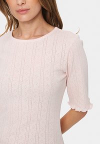 Šviesiai rožinė trumpų rankovių suknelė su tekstūruotu vertikalių juostelių ir mažų diamond formų raštu; turi apvalų iškirpimą ir palenkta rankovių kraštus.