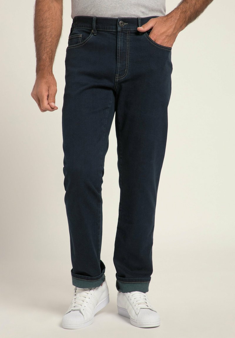 Granatowe dżinsy o slim fit z przednimi kieszeniami, zapięciem na guzik i podwiniętymi mankietami. W połączeniu z białymi trampkami.