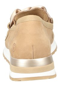 Baskets en daim beige avec un dos doux et arrondi, des accents métalliques dorés et une semelle en caoutchouc blanc avec une surface texturée.