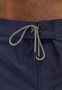 Costumi da bagno blu navy con chiusura a coulisse, motivo a zigzag bianco e nero, tessuto morbido e cuciture rinforzate per una maggiore durata.