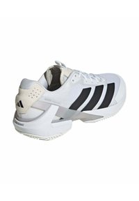 Scarpa da ginnastica bianca con strisce nere, tomaia in tessuto a rete testurizzato e suola ammortizzata. La parte posteriore presenta un tallone rialzato con accenti distintivi e logo.
