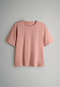 Kortärmad t-shirt i mjukt rosa bomullstyg, rund halsringning, avslappnad passform, slät struktur, minimalistisk design, inga synliga mönster eller detaljer.