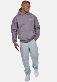 Gray hoodie with front pocket, light blue loose-fit jeans, and white sneakers. Casual look with a minimalistic design and soft texture.